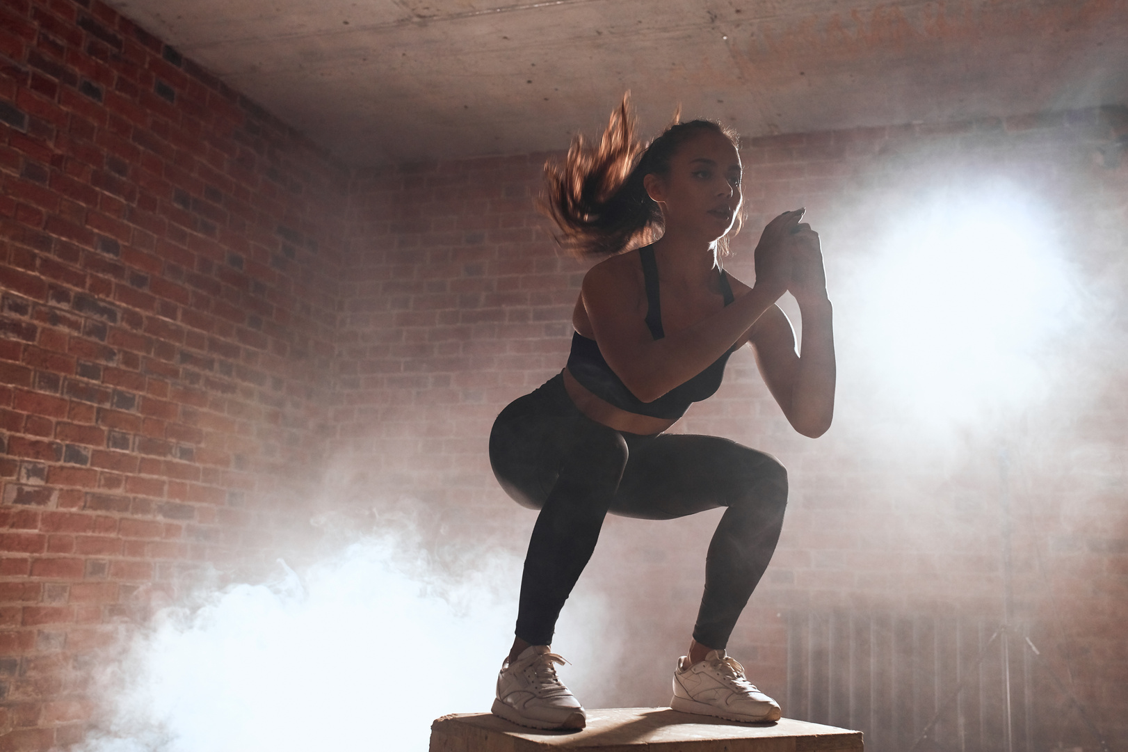 Sporty fit female doing jumping squats on fit box